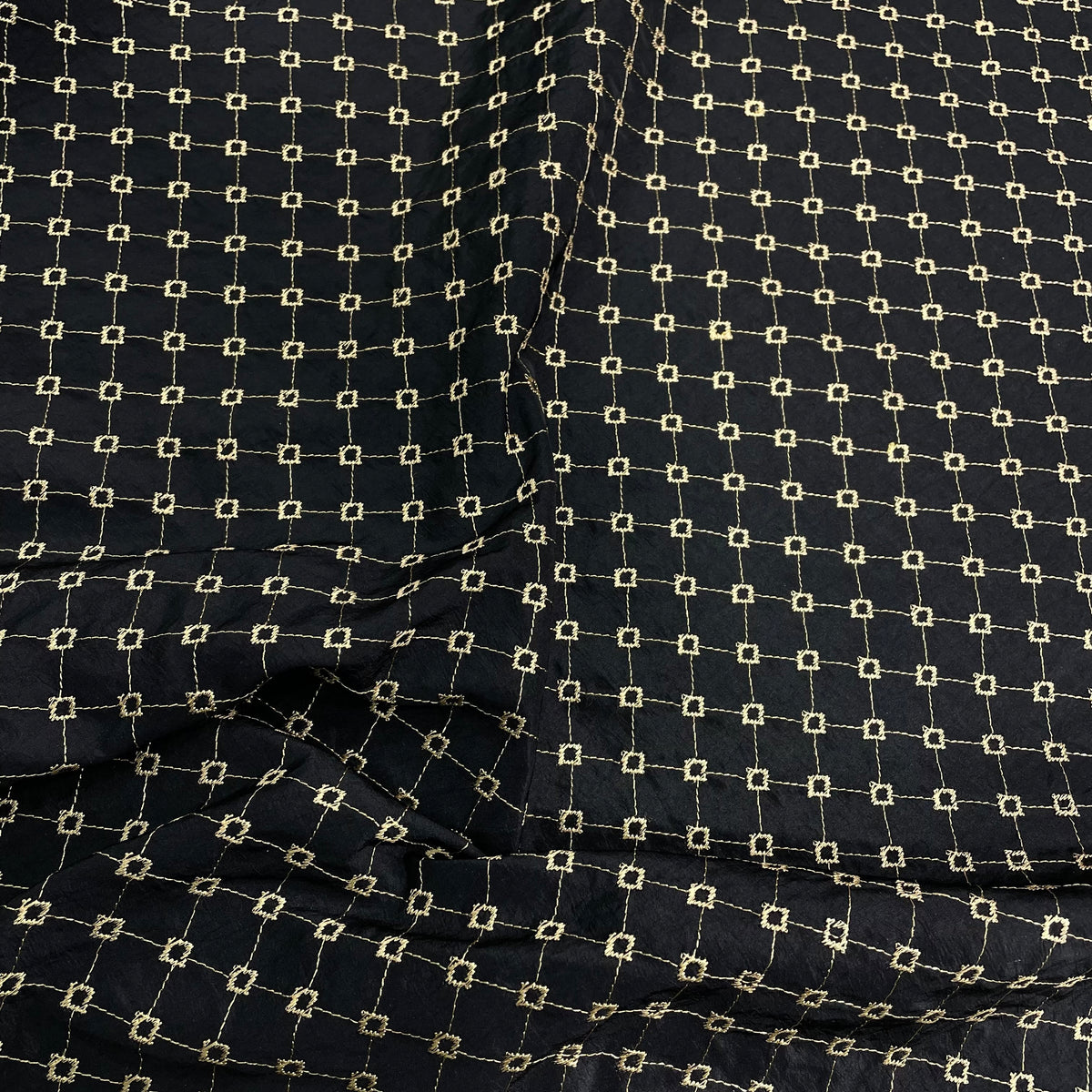Black and gold polyester taffeta fabric with a repeating geometric diamond pattern and subtle sheen