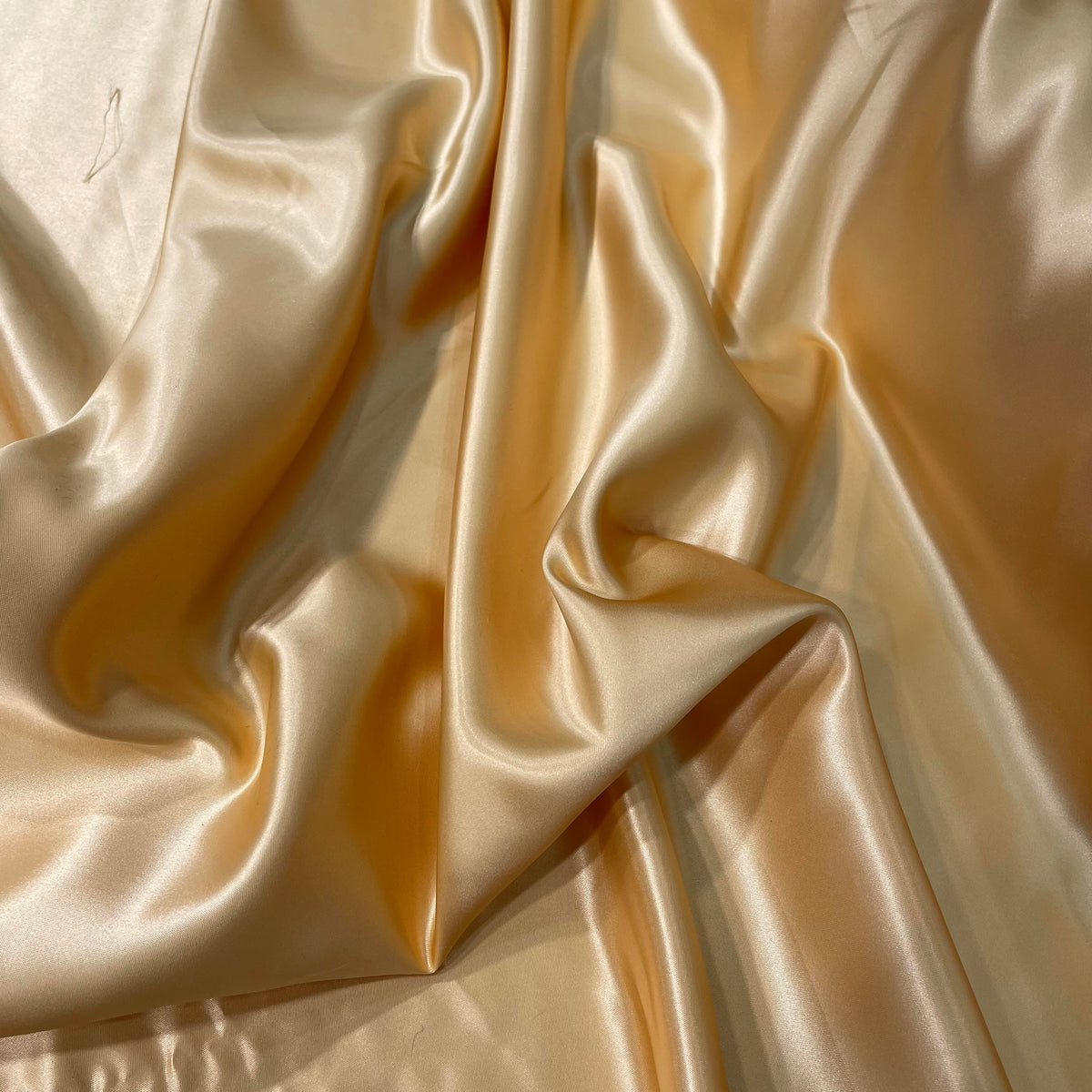 Cantaloupe yellow polyester satin fabric with a smooth lustrous surface and warm solid colour