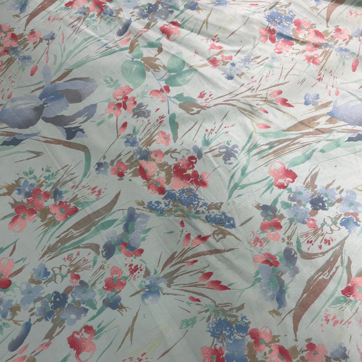 Blue cotton fabric with a soft pastel floral print