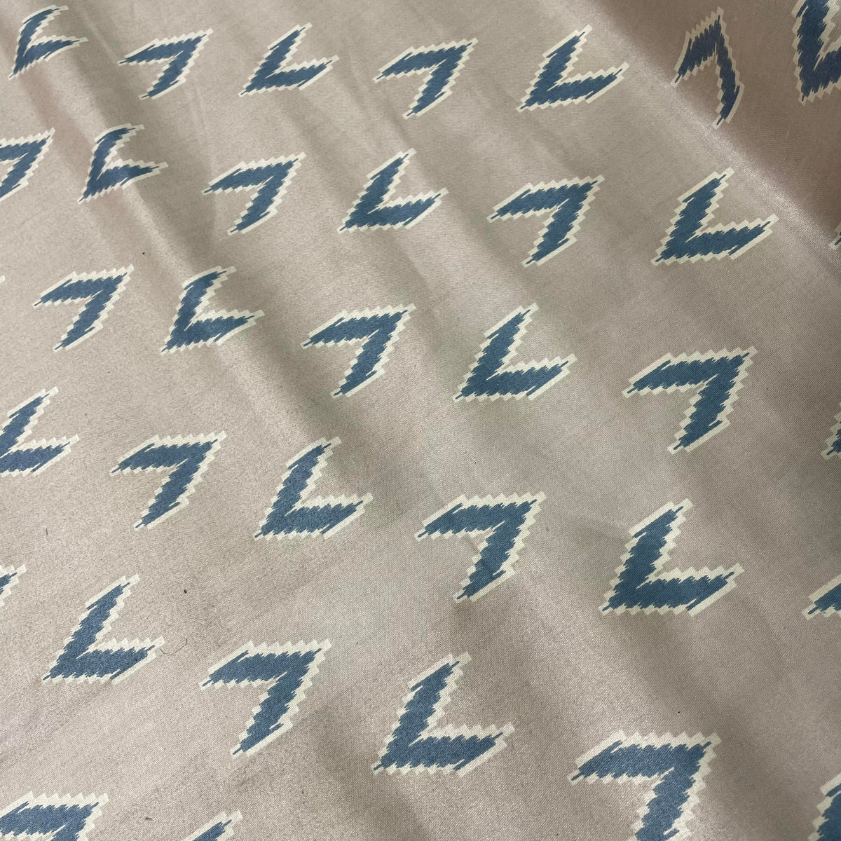 Taupe cotton fabric with a subtle darts-inspired pattern in soft beige and pink tones