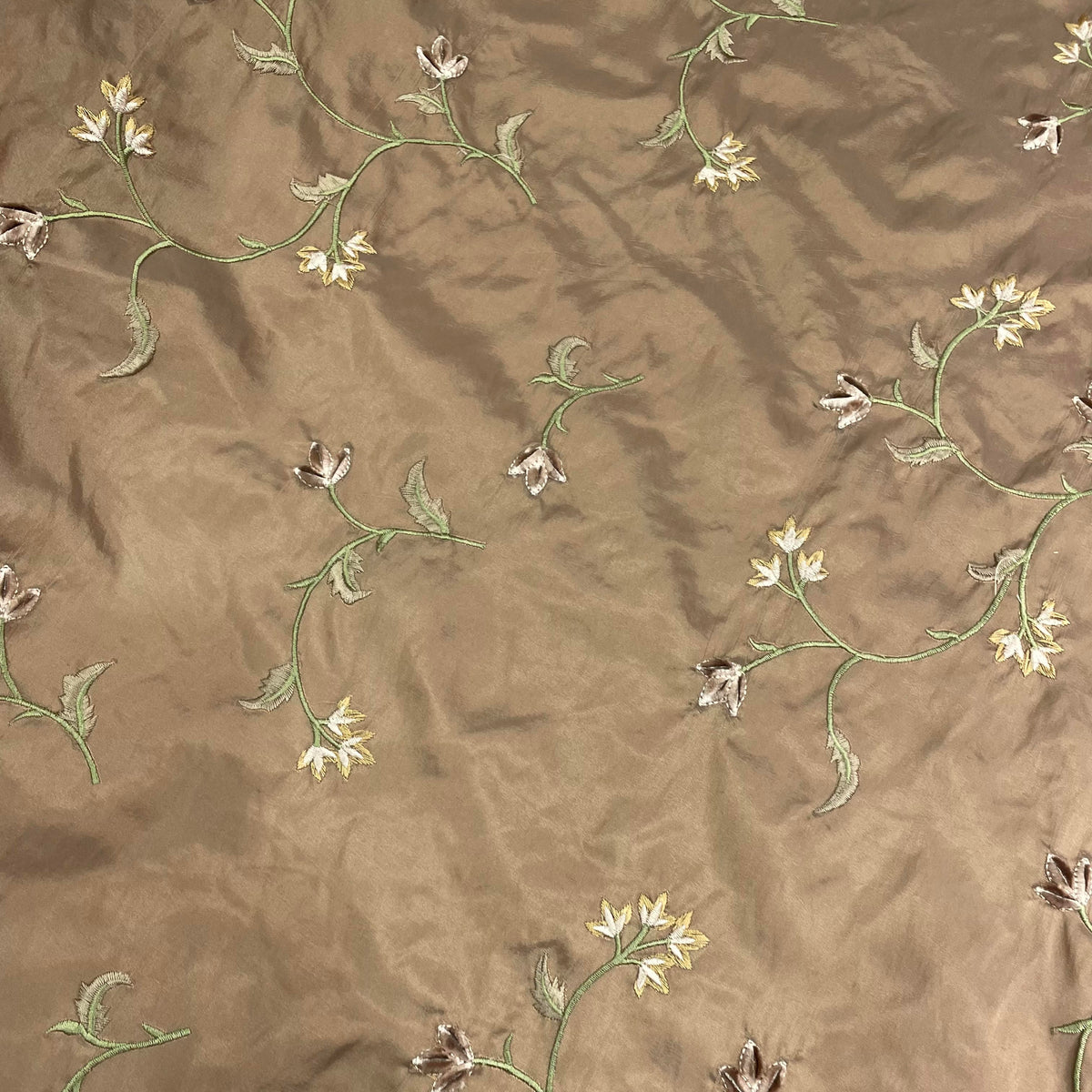 Beige polyester taffeta fabric with a decorative floral vine pattern and crisp structured surface