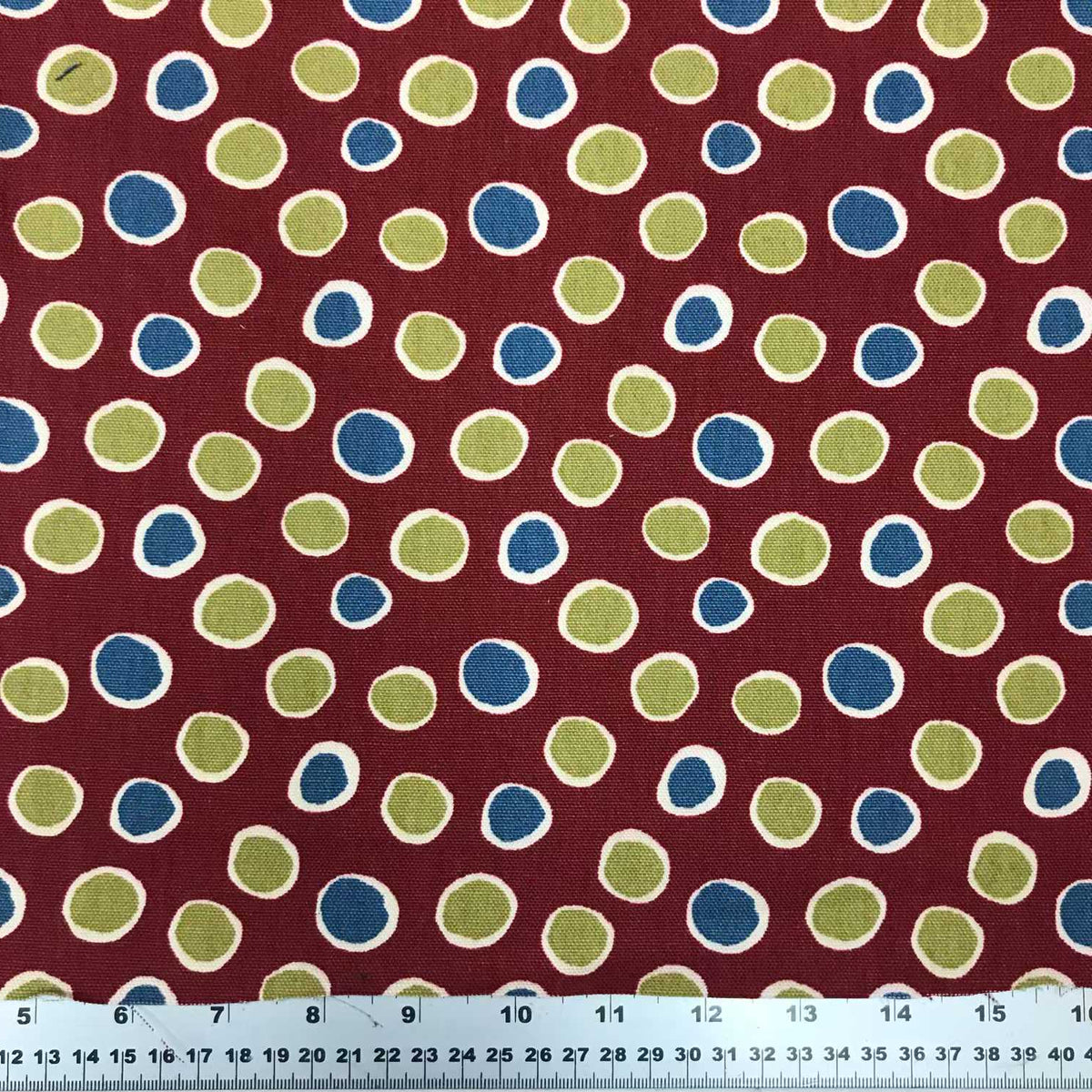 Red, blue, and green cotton fabric with a colourful repeating polka dot pattern