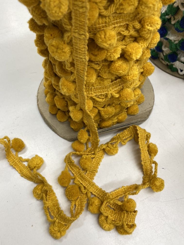 Yellow gold 1.25-inch pom pom trim with soft decorative tufts along a narrow trim base