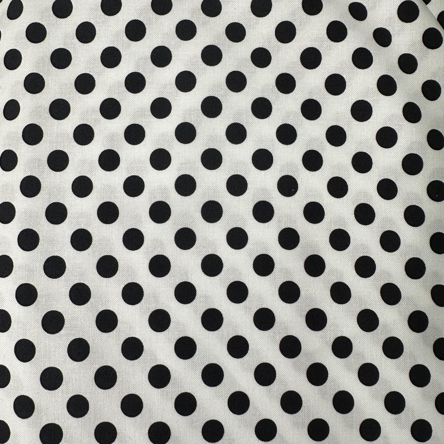 White cotton fabric with evenly spaced black polka dots