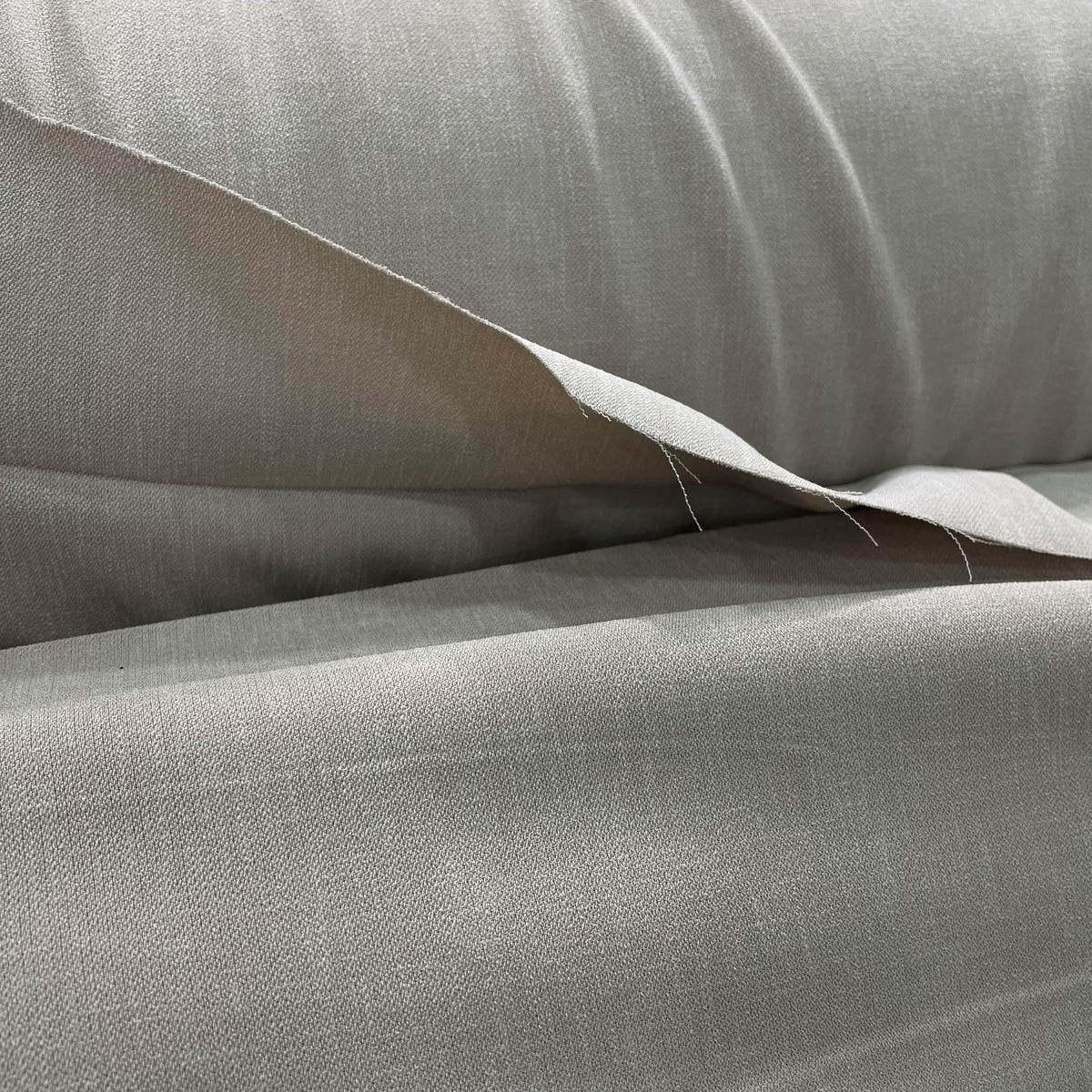Beige polyester fashion fabric with a lightweight woven appearance and solid neutral colour