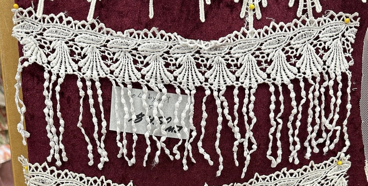 White 5-inch lace fringe trim with fan-like floral motifs and long knotted hanging strands