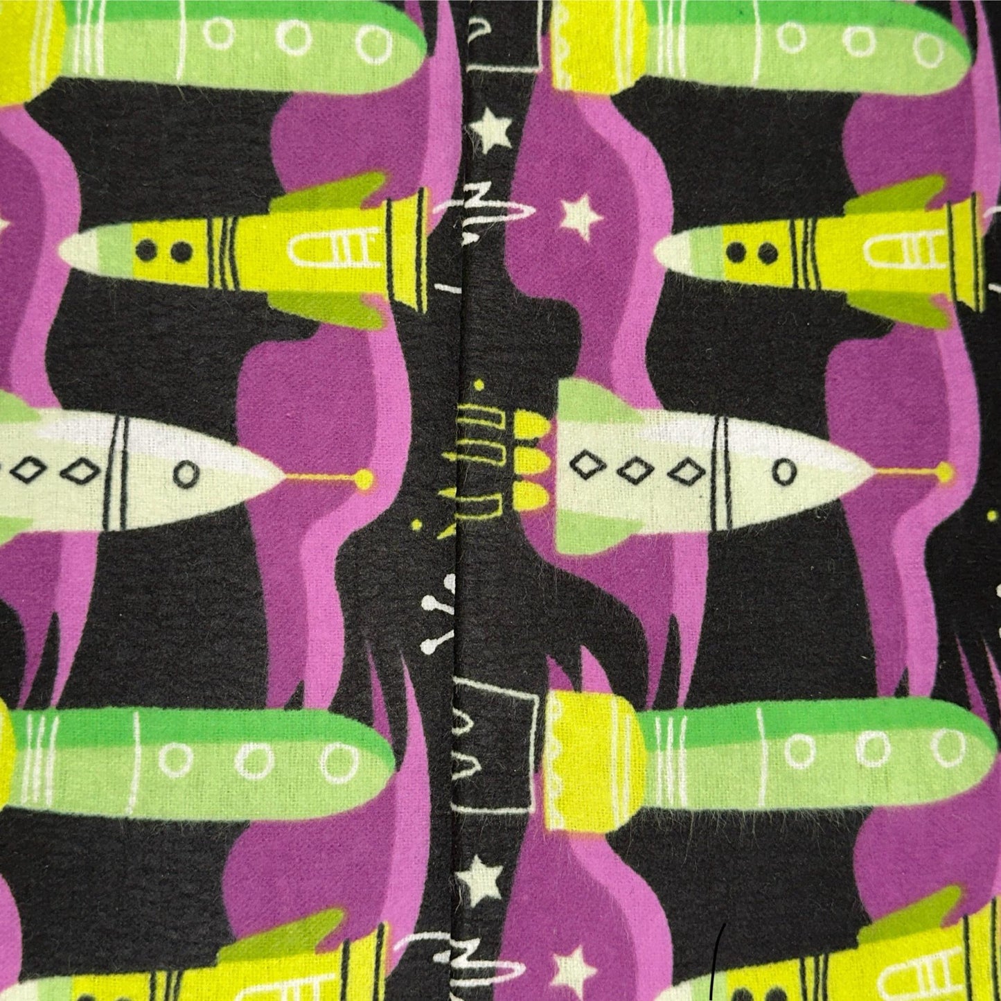 Black cotton flannel fabric with green, purple and white rockets, stars and space motifs