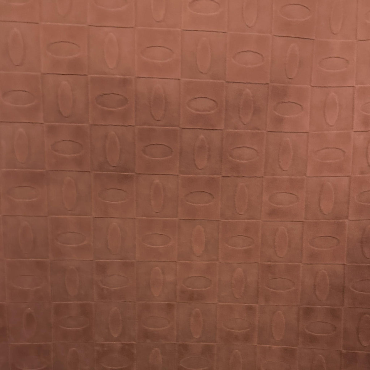 Pink velvet upholstery fabric with a geometric pattern of ovals set inside squares