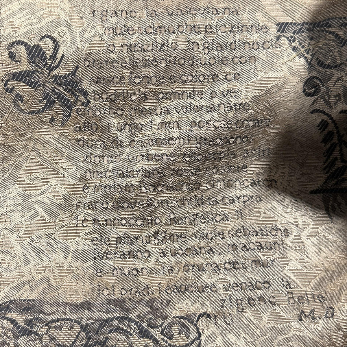 Beige polyester upholstery fabric with vintage script, scrollwork and ornamental motifs
