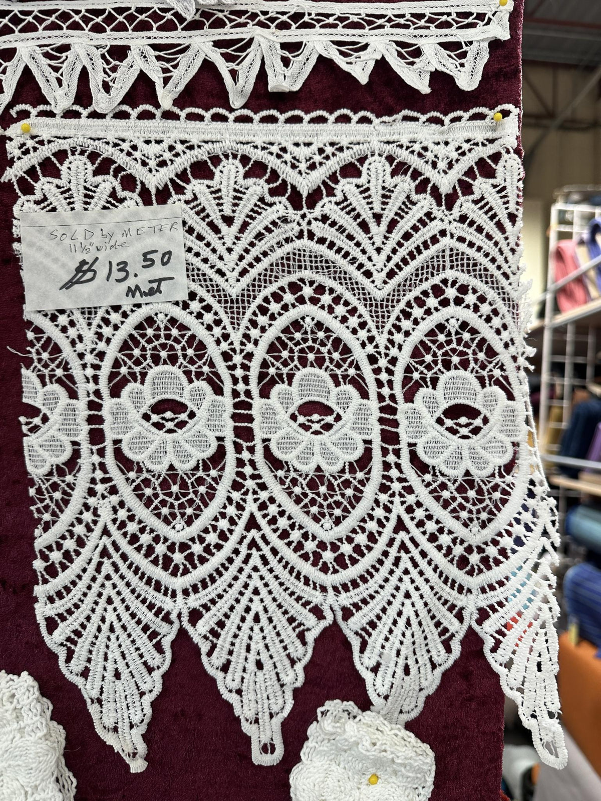 White 11.5-inch lace trim with floral medallions, oval motifs and a pointed scalloped edge