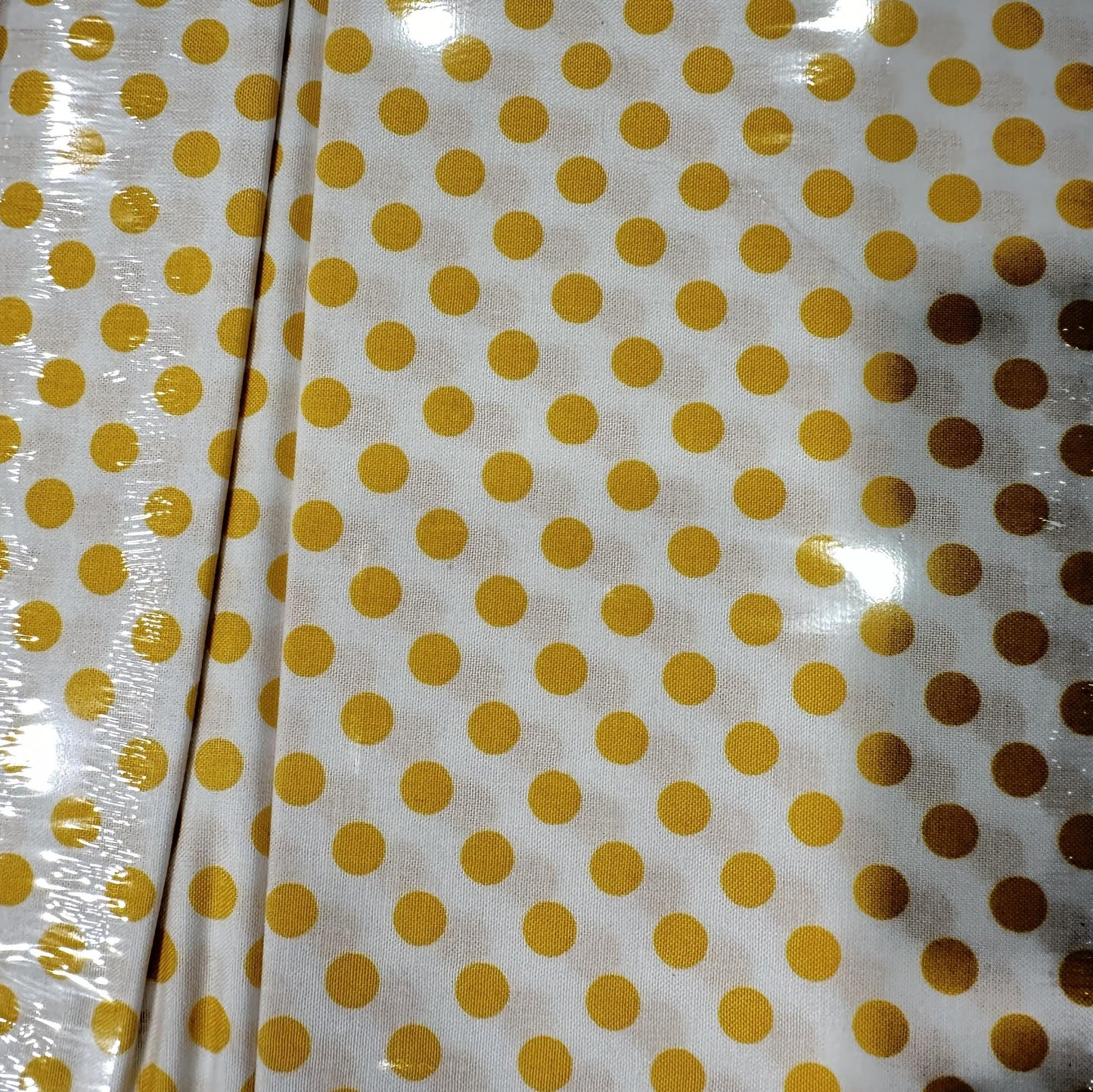 White cotton fabric with evenly spaced yellow polka dots