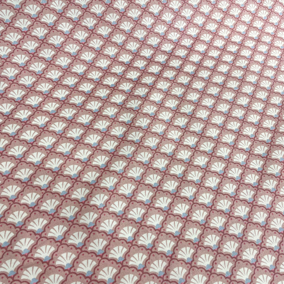 Pink cotton fabric with a repeating decorative scallop pattern