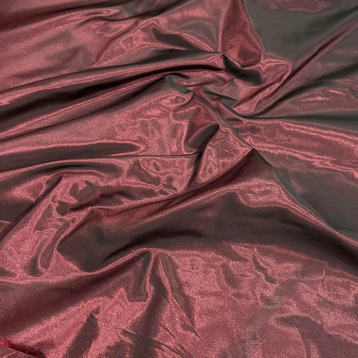 Red iridescent polyester taffeta fabric with a crisp surface and colour-shifting sheen